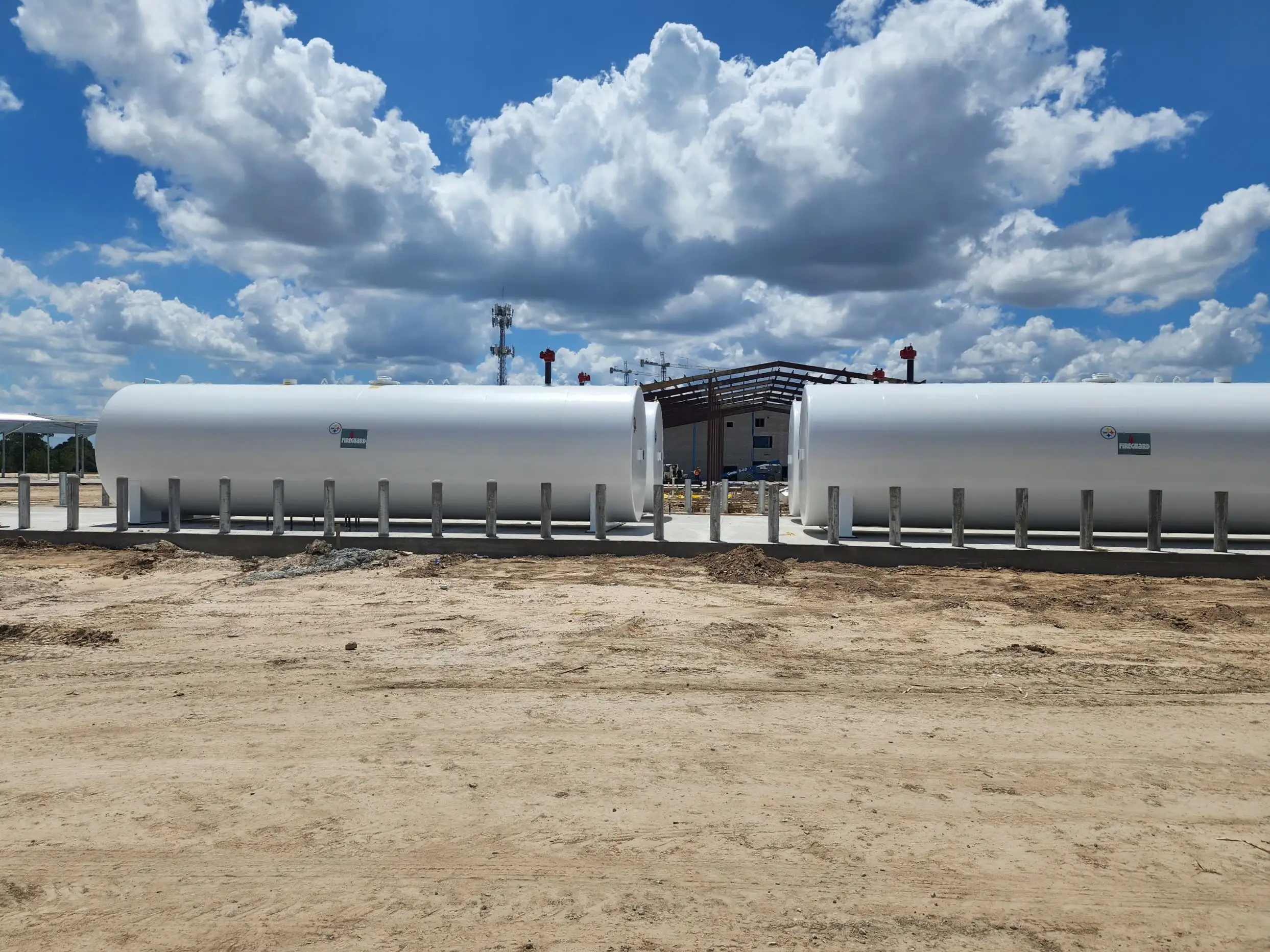 Two white above ground fuel storage tanks behind bollards on a new concrete pad
