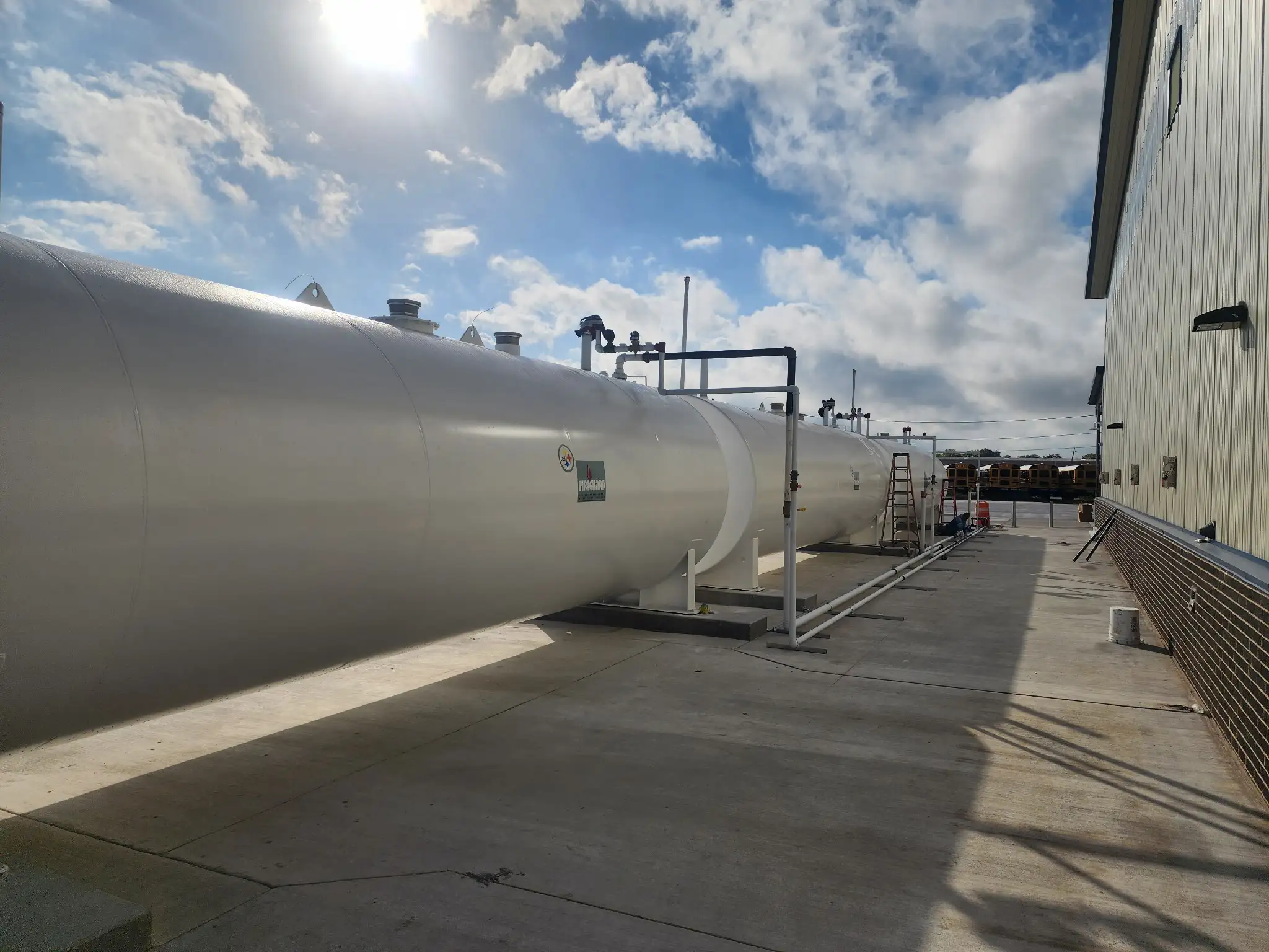 The finished tank line viewed from ground level with school buses visible in the distance