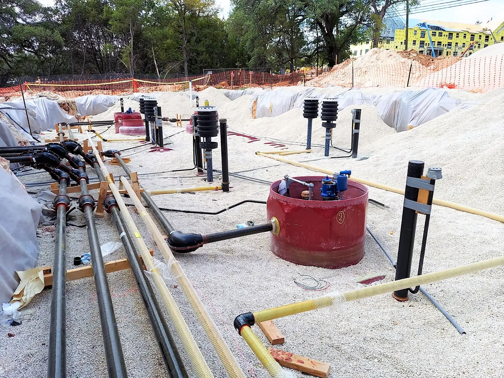 Triple wall product piping run across a prepared gravel bed before backfill